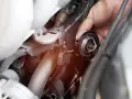 Mano che rimuove il termostato dell'auto. Un bulbo radiatore rotto può causare surriscaldamento.