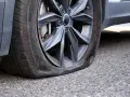 Ruota dell'auto con pneumatico sgonfio, mostra un'ernia evidente. Un problema comune che richiede attenzione immediata.