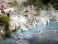 Persone si rilassano nelle calde acque delle terme di Petriolo libere, tra rocce e vegetazione.