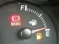 Cruscotto auto con spia freno a mano accesa e indicatore carburante quasi vuoto. È ora di fare rifornimento e resettare l'indicatore carburante.