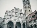 La cattedrale di San Martino a Lucca, con la sua imponente facciata in marmo bianco e il campanile romanico, domina la piazza.
