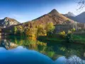 Lago incantevole con riflessi di montagne e boschi autunnali. Un borgo in pietra completa il paesaggio, ideale per scoprire dove andare in montagna in Toscana.