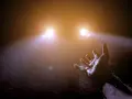 Mano tesa verso le luci abbaglianti di un'auto nella nebbia, un momento di incertezza e speranza.