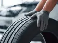 Mani guantate controllano il battistrada di uno pneumatico, valutando la sua durata gomme auto.