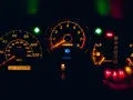 Cruscotto auto illuminato di arancione: tachimetro, contagiri, indicatori di marcia e spie accese, tra cui una spia arancione macchina.