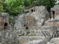 Antiche tombe scavate nella roccia, parte dei siti etruschi in Toscana, con sentieri e recinzioni in legno.