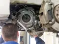 Meccanico lavora sulla frizione di un'auto. La durata della frizione varia, ma si consiglia di controllarla ogni quanti km si cambia la frizione.