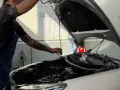 Meccanico con tatuaggi controlla il motore. Per sapere tagliando auto ogni quanto, consulta il libretto o chiedi al tuo meccanico di fiducia.