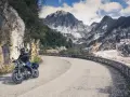 Un motociclista percorre una strada tortuosa tra le cave di marmo delle Alpi Apuane, un'avventura tra i passi toscana moto.