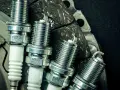 Candele auto benzina: scopri ogni quanto cambiarle per un motore efficiente. Nuove candele in primo piano su uno sfondo scuro.