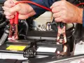 Mani che collegano i cavi alla batteria per capire come far ripartire la macchina.