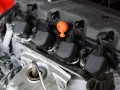 Dettaglio del motore con bobina macchina, candela e tappo arancione.