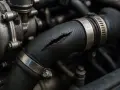 Manicotto radiatore rotto, un sintomo di problemi al motore. La crepa è visibile, con liquido che fuoriesce.