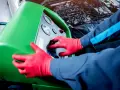 Tecnico con guanti rossi usa una macchina per controllare la perdita gas condizionatore auto.