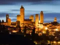 San Gimignano, una delle città più belle della Toscana, illuminata di notte con le sue iconiche torri medievali che svettano nel cielo.