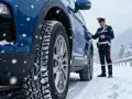 Agente controlla pneumatici invernali su auto blu in nevicata, rispettando art. 79 cds.