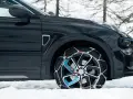 Auto nera su neve con catene sulle ruote motrici per affrontare il ghiaccio.
