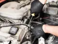Meccanico con guanti neri lavora sul motore, risolvendo problemi pompa gasolio serbatoio.