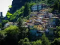 Case colorate e tetti rossi si aggrappano alla collina a Casoli di Camaiore, circondate da un verde lussureggiante.