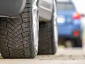 Primo piano di pneumatici invernali, con un'altra auto in lontananza. La classe rumorosità pneumatici è un fattore importante per il comfort di guida.