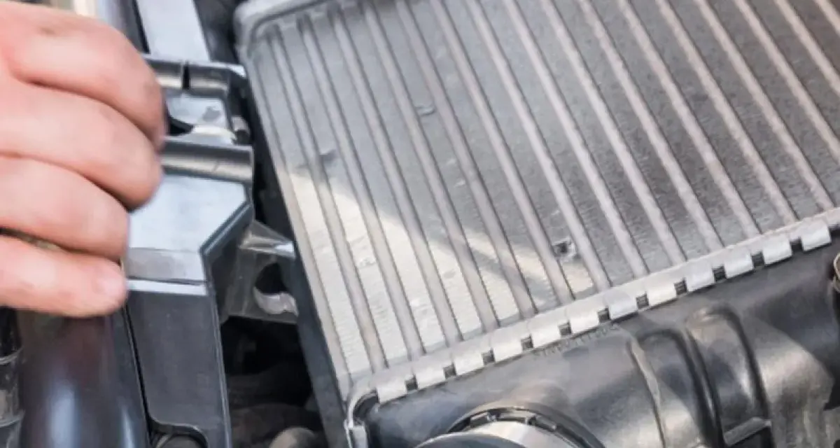 Mano che controlla un intercooler che sfiata, parte essenziale del sistema di sovralimentazione di un motore.