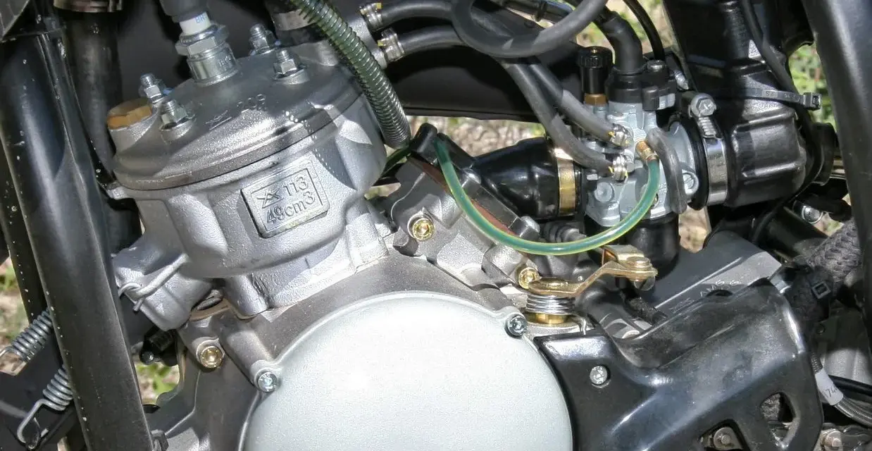 Dettaglio motore 49cc, con carburatore e candela. Potrebbe essere utile per diagnosticare sintomi motore aspira aria.