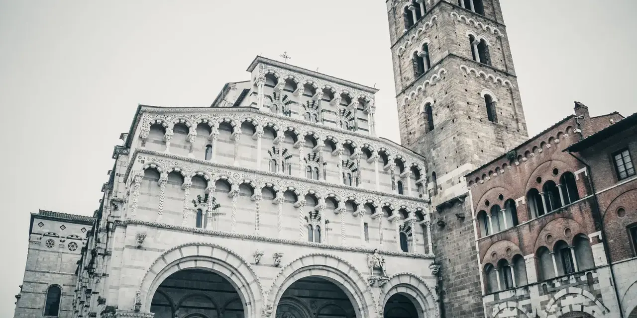 La cattedrale di San Martino a Lucca, con la sua imponente facciata in marmo bianco e il campanile romanico, domina la piazza.