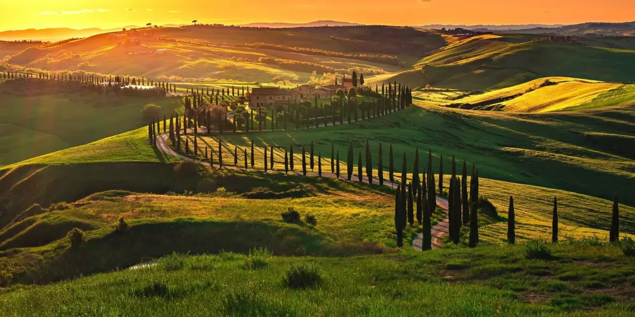 Colline toscane al tramonto, con cipressi che fiancheggiano una strada sinuosa, come una mappa della strada del vino toscana.