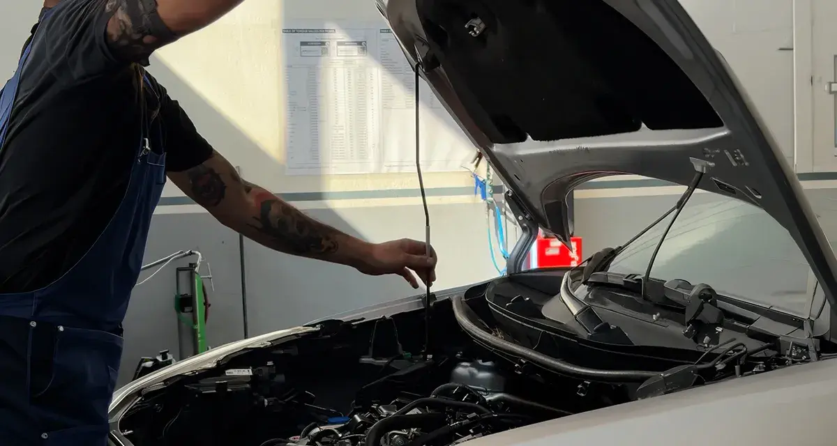 Meccanico con tatuaggi controlla il motore. Per sapere tagliando auto ogni quanto, consulta il libretto o chiedi al tuo meccanico di fiducia.