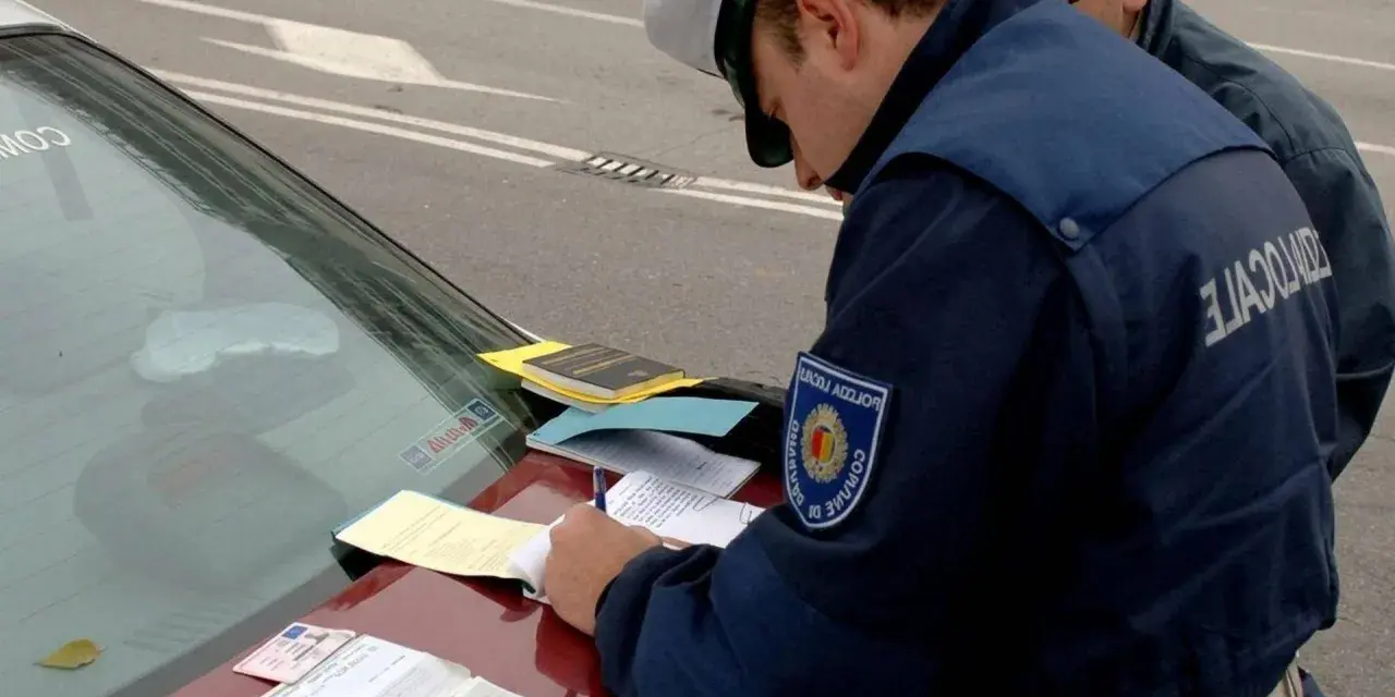 Agente di polizia scrive verbale su un'auto con revisione scaduta da 2 anni. Documenti e patente sul cofano.