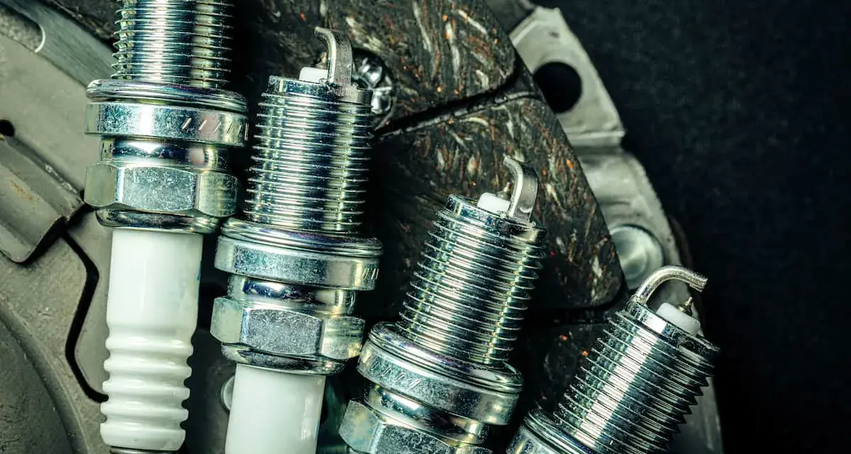 Candele auto benzina: scopri ogni quanto cambiarle per un motore efficiente. Nuove candele in primo piano su uno sfondo scuro.