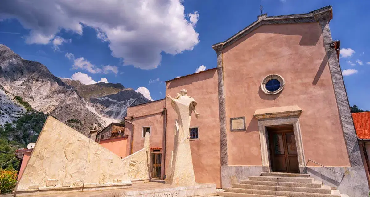 Monumento ai cavatori e chiesa a Colonnata, con le Alpi Apuane sullo sfondo. Un luogo suggestivo da scoprire, tra arte e storia.