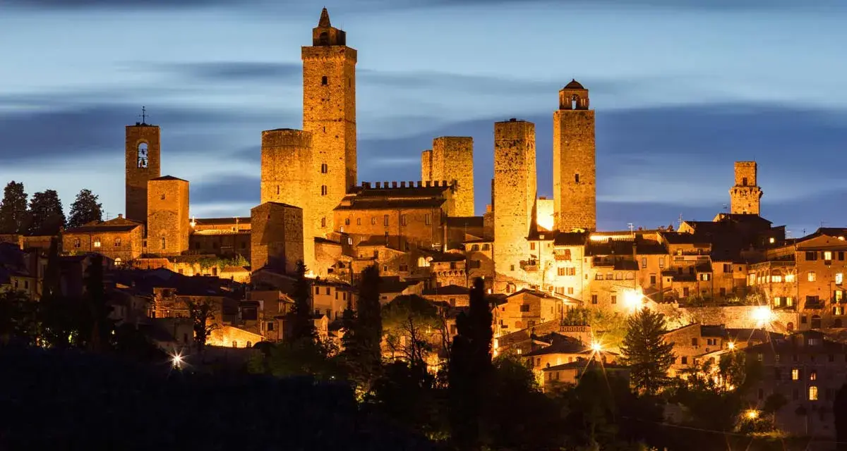 San Gimignano, una delle città più belle della Toscana, illuminata di notte con le sue iconiche torri medievali che svettano nel cielo.
