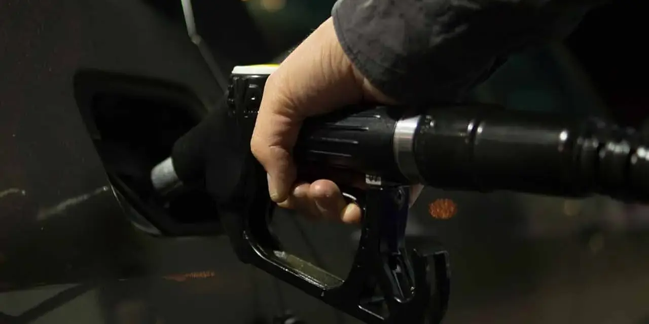 Mano che inserisce la pistola del carburante nel serbatoio dell'auto. Potrebbe indicare una pompa della benzina rotta o sintomi di malfunzionamento.