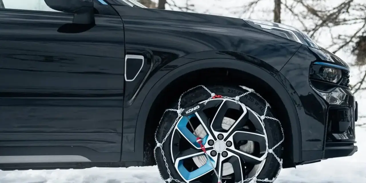 Auto nera su neve con catene sulle ruote motrici per affrontare il ghiaccio.