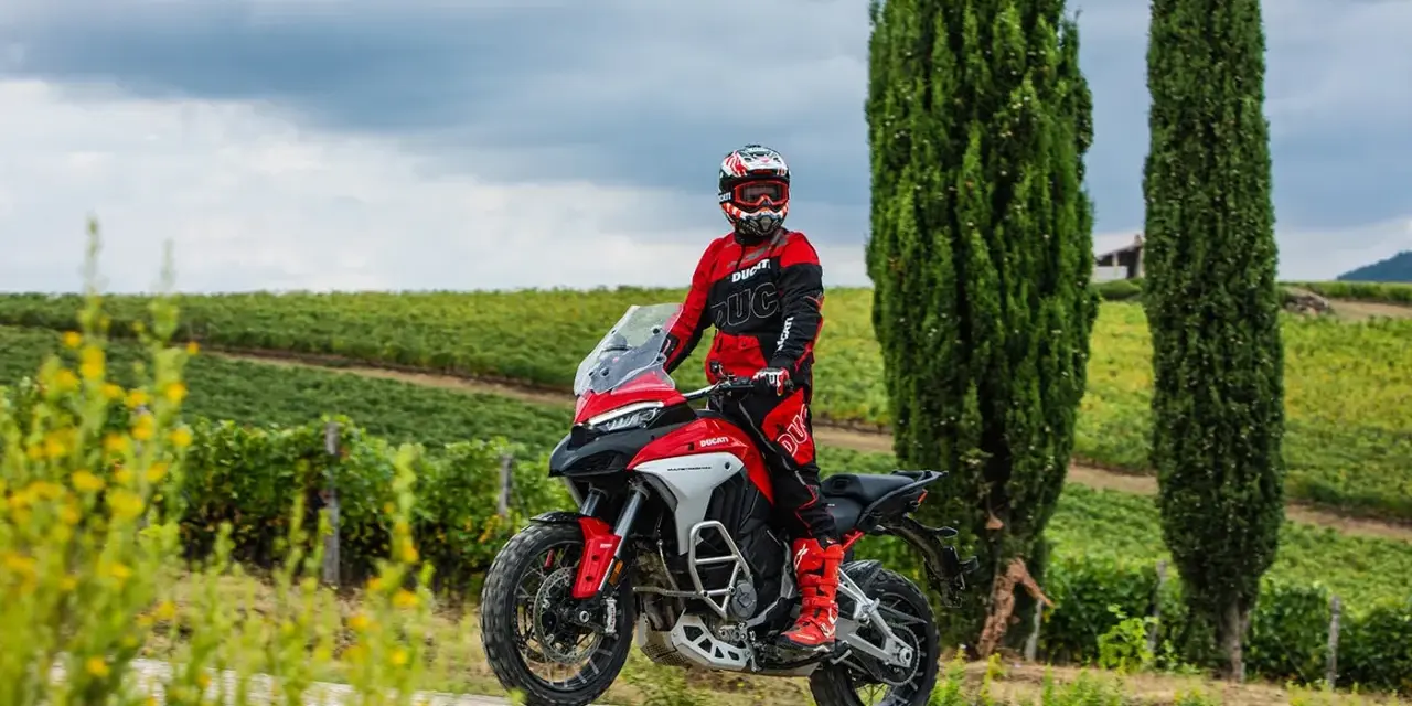 Motociclista in tenuta da gara su una Ducati, pronto per itinerari moto Toscana 1 giorno tra vigneti e cipressi.