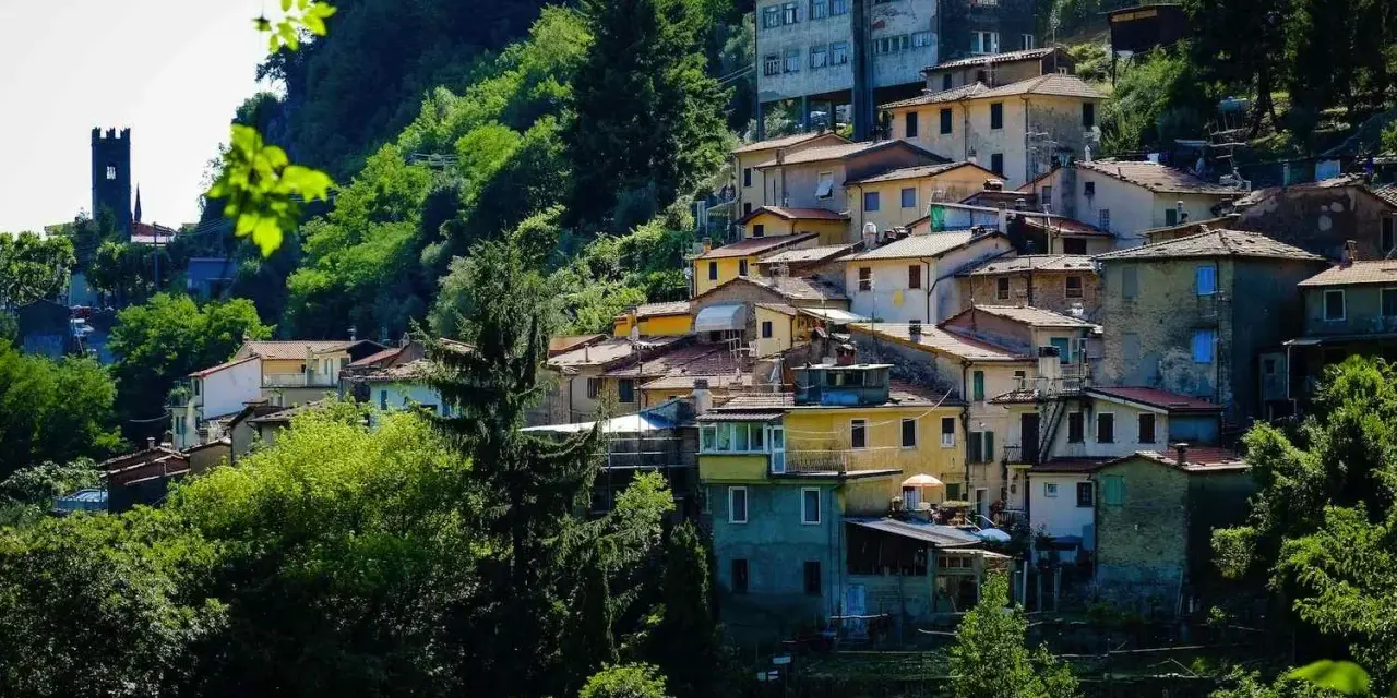 Case colorate e tetti rossi si aggrappano alla collina a Casoli di Camaiore, circondate da un verde lussureggiante.