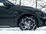 Auto nera su neve con catene sulle ruote motrici per affrontare il ghiaccio.