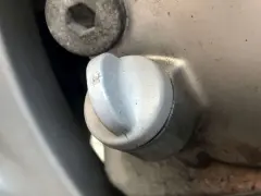 Dettaglio di un tappo motore con una piccola crepa, suggerendo una possibile fuoriuscita olio motore dal tappo.