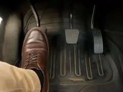 Scarpa marrone su pedale della frizione abbassata, pronta a cambiare marcia.