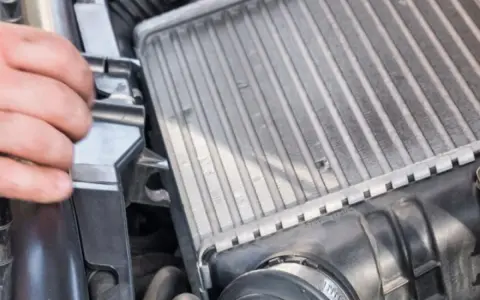 Mano che controlla un intercooler che sfiata, parte essenziale del sistema di sovralimentazione di un motore.