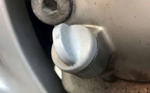 Dettaglio di un tappo motore con una piccola crepa, suggerendo una possibile fuoriuscita olio motore dal tappo.