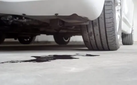 Macchia scura sull'asfalto, probabile perdita d'acqua dal termostato auto rotto.