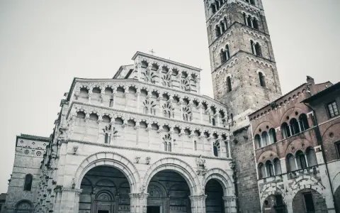 La cattedrale di San Martino a Lucca, con la sua imponente facciata in marmo bianco e il campanile romanico, domina la piazza.