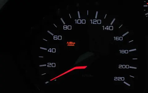 Cruscotto auto con spia AdBlue accesa, indica che il livello del liquido è basso o c'è un problema.
