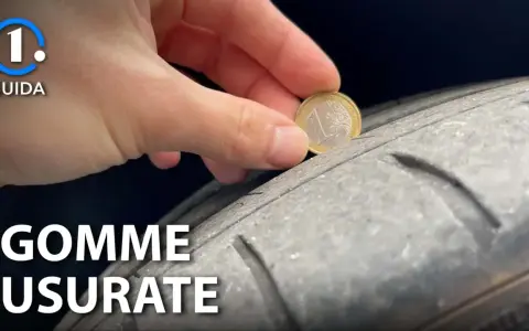 Una mano inserisce una moneta da 1 euro in un pneumatico usurato, indicando che è consigliabile sostituire gli pneumatici per la sicurezza.