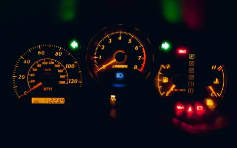 Cruscotto auto illuminato di arancione: tachimetro, contagiri, indicatori di marcia e spie accese, tra cui una spia arancione macchina.