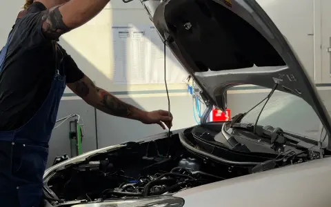 Meccanico con tatuaggi controlla il motore. Per sapere tagliando auto ogni quanto, consulta il libretto o chiedi al tuo meccanico di fiducia.