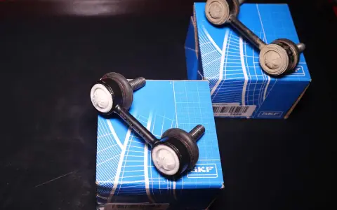 Biellette barra stabilizzatrice rotte sintomi: due nuove biellette SKF su scatole blu, una usata e sporca.