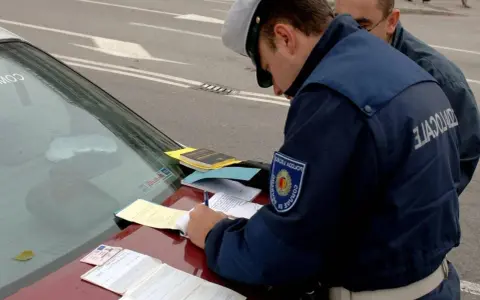 Agente di polizia scrive verbale su un'auto con revisione scaduta da 2 anni. Documenti e patente sul cofano.